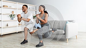 Athletic black couple doing lunges on home workout, copy space. Domestic training during covid lockdown