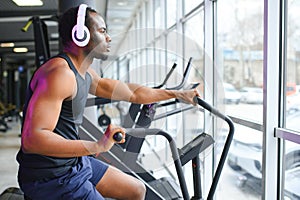 Athletic black man doing cardio workout on exercise bike in gym. Concept of sport and healthy lifestyle