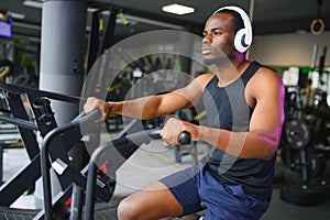 Athletic black man doing cardio workout on exercise bike in gym. Concept of sport and healthy lifestyle