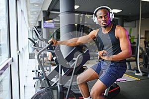 Athletic black man doing cardio workout on exercise bike in gym. Concept of sport and healthy lifestyle