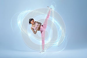 Athletic black woman doing karate side kick, clenching fists and raising leg, standing over blue neon studio background