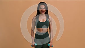 Athletic Black Woman Exercising With Dumbbells Flexing Arms, Beige Background