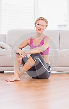 Athletic blonde sitting on floor smiling at camera