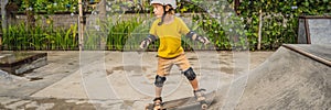 Athletic boy in helmet and knee pads learns to skateboard with in a skate park. Children education, sports BANNER, LONG