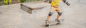 Athletic boy in helmet and knee pads learns to skateboard with in a skate park. Children education, sports BANNER, LONG