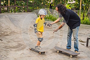 Athletic boy learns to skateboard with a trainer in a skate park. Children education, sports