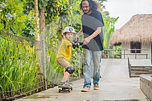 Athletic boy learns to skateboard with a trainer in a skate park. Children education, sports