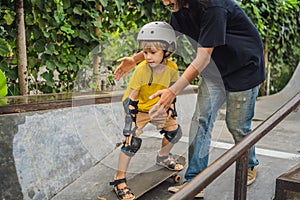 Athletic boy learns to skateboard with a trainer in a skate park. Children education, sports