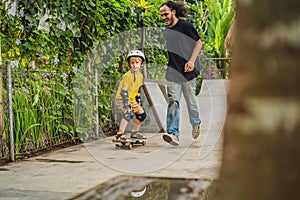 Athletic boy learns to skateboard with a trainer in a skate park. Children education, sports