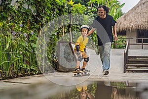 Athletic boy learns to skateboard with a trainer in a skate park. Children education, sports