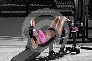 Athletic brunette woman doing some crunches in a bench at the gym