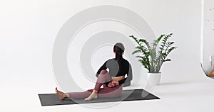 Athletic brunette woman practicing yoga, performing a variation of the Ardha Matsyendrasana exercise