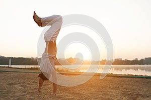 Athletic capoeira performer workout training on the beach sunris