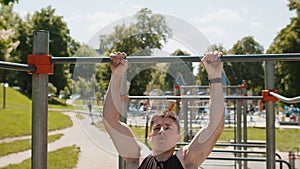 Athletic caucasian man in sportswear doing pull ups exercises on horizontal bar, pumping up back