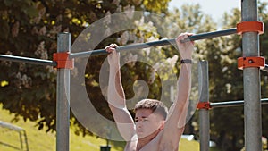 Athletic caucasian topless muscular man doing pull ups exercises on horizontal bar, pumping up back