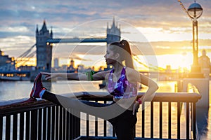 Athletic city woman does her stretches in front of Tower Bridge in London