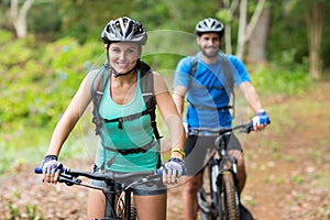 Athletic couple cycling in forest