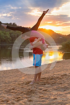 Athletic couple doing yoga at sunset on a beach