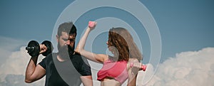 Athletic couple of fit man and woman with a dumbells outdoors. Couple doing fitness outside. Young fitness couple