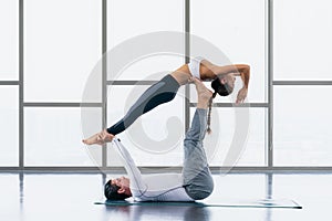 Athletic couple practicing acro yoga or yoga partner together in gym