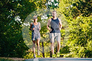Athletic couple running on sunset in the city park