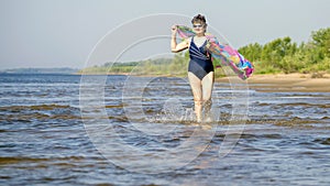 Athletic elderly woman runs along the waves on a summer sunny day against the background of mountains