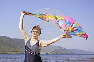 Athletic elderly woman runs along the waves on a summer sunny day