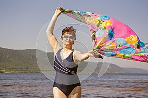 Athletic elderly woman runs along the waves on a summer sunny day