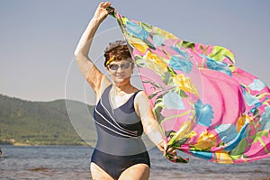 Athletic elderly woman runs along the waves on a summer sunny day