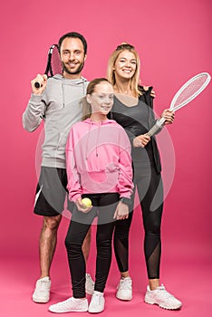 athletic family holding tennis rackets and ball, isolated photo