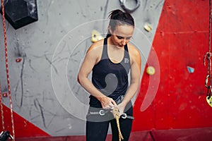 Woman climber tying rope in knot and preparing to climb. Climbing equipment