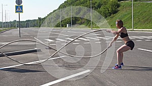 Athletic female working out using battle ropes. Crossfit