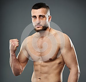 Athletic fighter posing on gray
