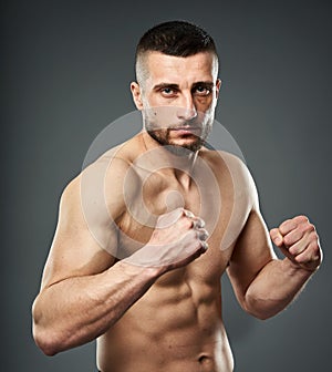 Athletic fighter posing on gray