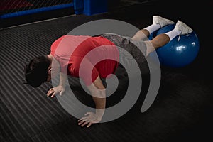 An athletic and fit asian man does pushups on a stability ball. Abdominal and core exercise and workout. Overhead shot