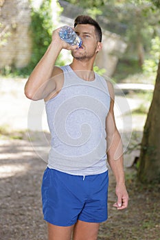 athletic fit man drinking water after running workout