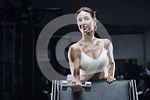 Athletic fitness woman in gym with dumbbell