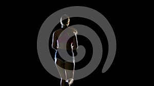 Athletic fitness woman running rear view on a black background. Silhouette