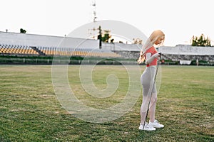 Athletic Girl Doing Jump Rope Exercises in Red Top. Woman Doing Physical Exercises in Stadium