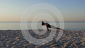 Athletic girl doing some yoga exercises on the sand against the sea and sky at sunrise.healthy lifestyle,enjoyment, harmony. 4k.