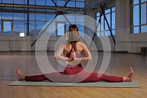 athletic girl doing yoga asana in a studio with large windows