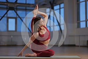 athletic girl doing yoga asana in a studio with large windows