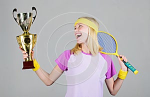 Athletic girl hold tennis racket and golden goblet. Win tennis game. Woman wear sport outfit. Tennis player win