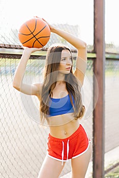 Athletic girl holding up a basketball ball