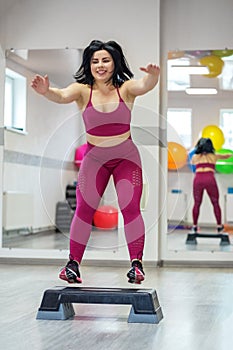 Athletic girl jumping on stepper in the gym. Exercise muscle. The concept of sports, a healthy lifestyle, losing weight