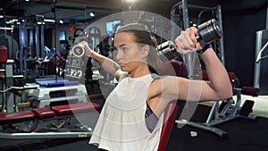 Athletic girl is pumping muscles of her arms