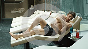 Athletic guy drinking cocktail in spa. Sexy man relaxing in wellness center.