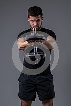 Athletic guy performing one dumbbell front raise