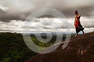 Athletic guy standing on a rock on a background of a stormy sky. Sri Lanka. Mulkirigala Raja Maha Viharaya. View from above