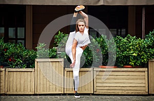 Athletic gymnast girl doing stretching exercises at facade house